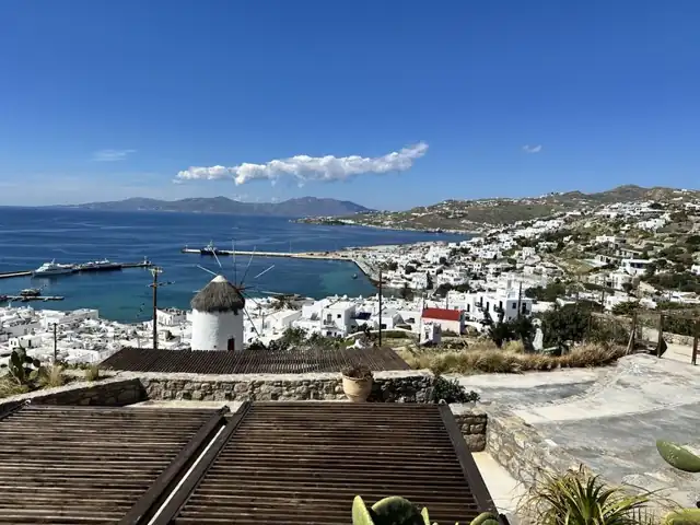 A white windmill and buildings overlooking a Greek island harbor