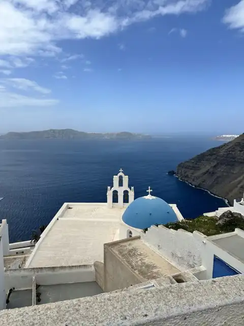 A blue-domed church above the sea in Greece, photographed during Felicia’s travels
